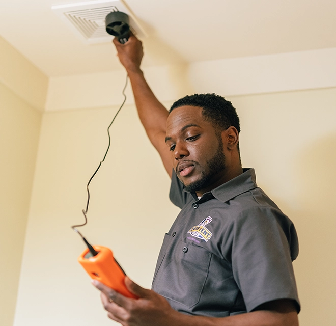Technician holding a device to the bath fan.