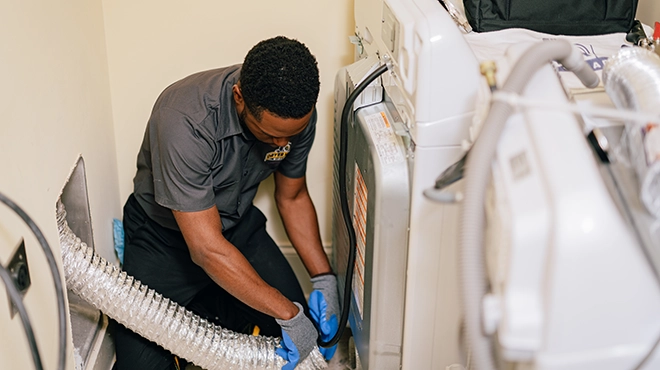 Technician cleaning inside of an aluminum dryer vent duct.