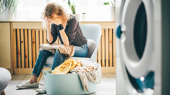 Woman sitting near pile of laundry.