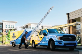 Dryer Vent Wizard professional unloads ladder from company truck in preparation to clean dryer vents in apartment complex.
